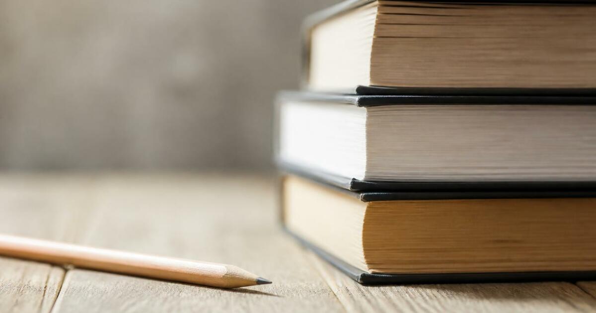 Университет «НЕЙМАРК» проведет День открытых дверей 21 июня Стопка книг и карандаш на деревянной поверхност...