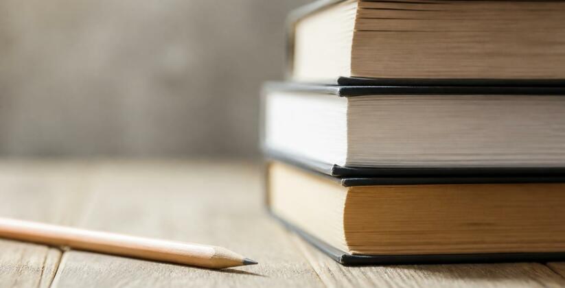 Университет «НЕЙМАРК» проведет День открытых дверей 21 июня Стопка книг и карандаш на деревянной поверхност...